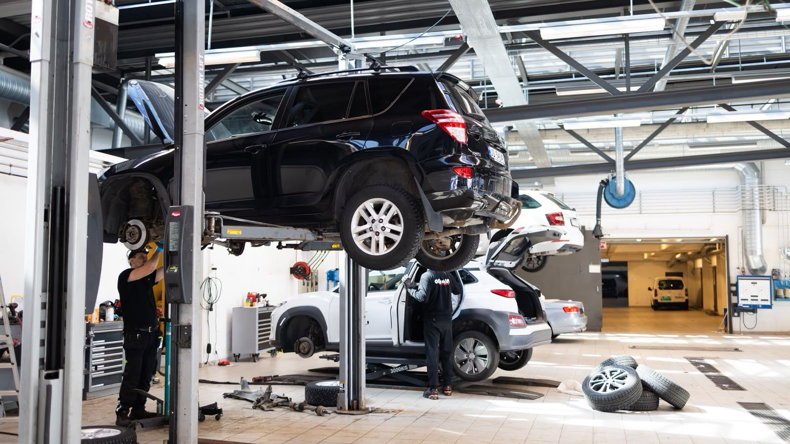 Car on the lift, EV with the wheel off and seasonal wheels on the floor